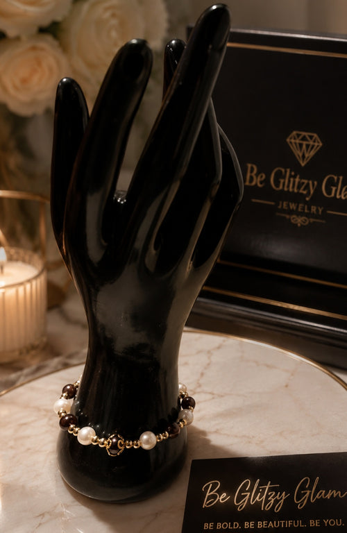 Crimson and pearl bracelet with gold accent beads displayed on a black hand jewelry stand