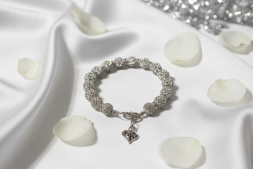 Crystal rhinestone disco ball heart charm bracelet on white satin with rose petals