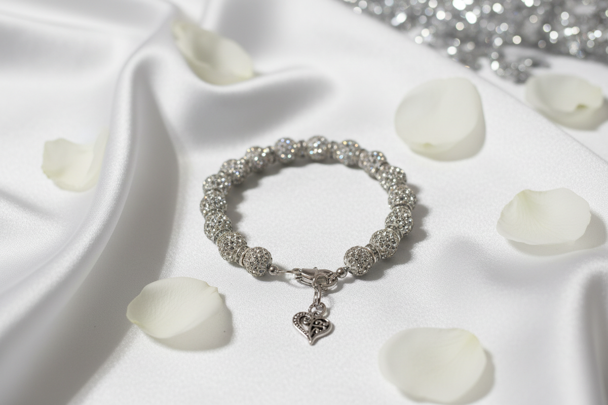Crystal rhinestone disco ball heart charm bracelet on white satin with rose petals