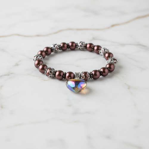 Brown pearl bracelet with heart charm on white marble — elegant product photo